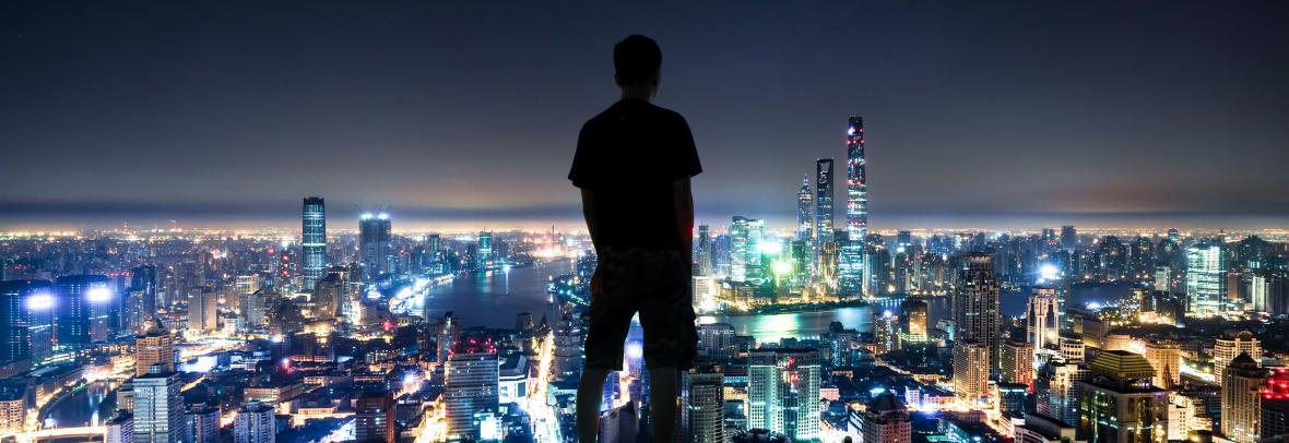 Man looking at nighttime skyline of Shanghai