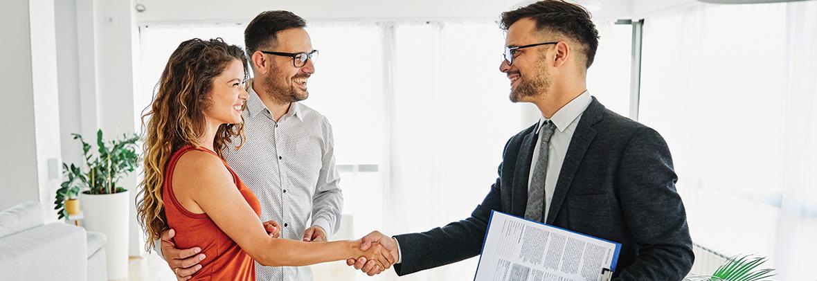 Photo of a male realtor shaking the hands of a couple
