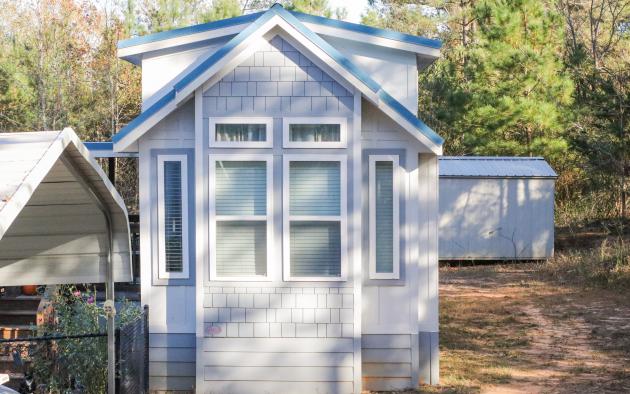 Blue tiny home with carport and storage in the back