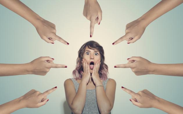 Upset woman surrounded by 7 fingers pointed at her
