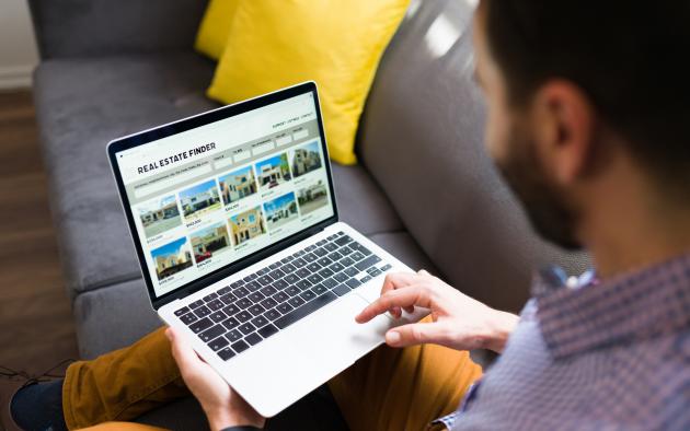 Man looking at real estate listings on a laptop