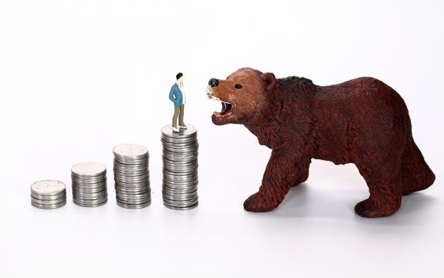 A toy bear growls at a man standing on top of a stack of coins