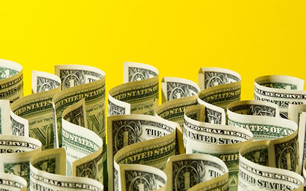 Photo illustration of dollar bills in a wavy pattern on a yellow background