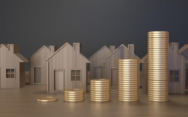 small wooden block houses with stacks of gold coins in front