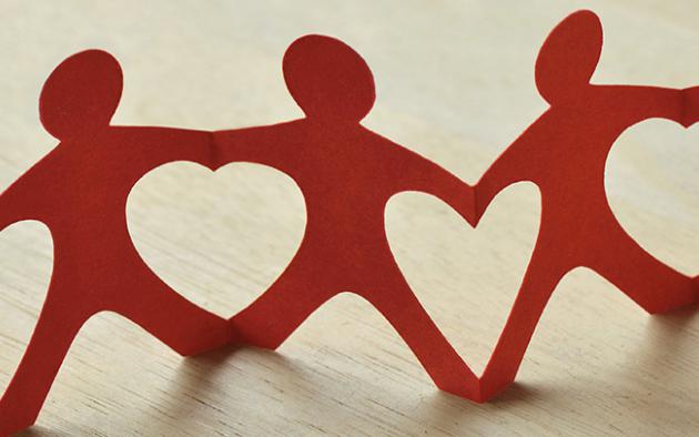 paper cut outs of people holding hands creating heart shapes in between