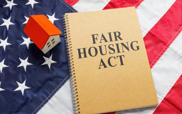 fair housing act on notebook near tiny house on American flag