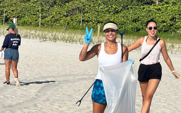 Two women on beach cleaning up trash
