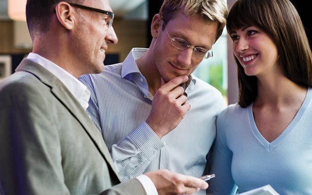 Photo of realtor with a couple handing a contract to sign