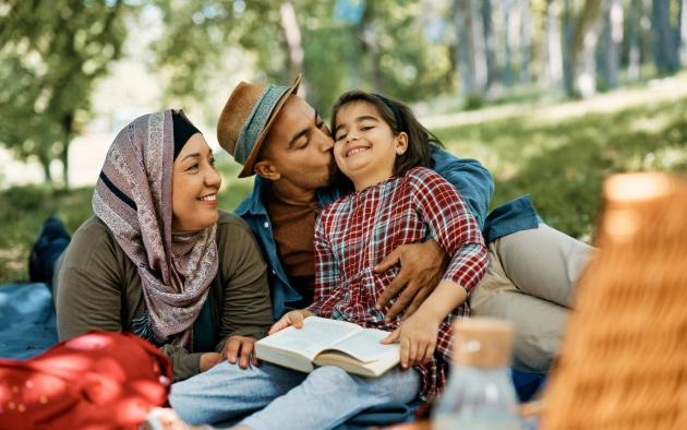 Muslim family with one child sitting outside reading