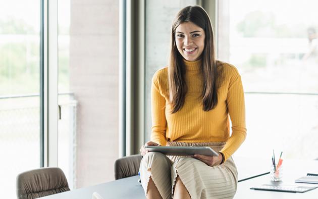 Photo of Millennial Realtor sitting on a desk using a tablet computer