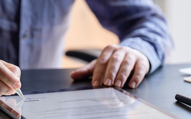 Photo of a man signing a contract on a tablet computer