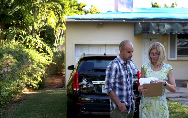Realtor reviewing paperwork with a client outside a home