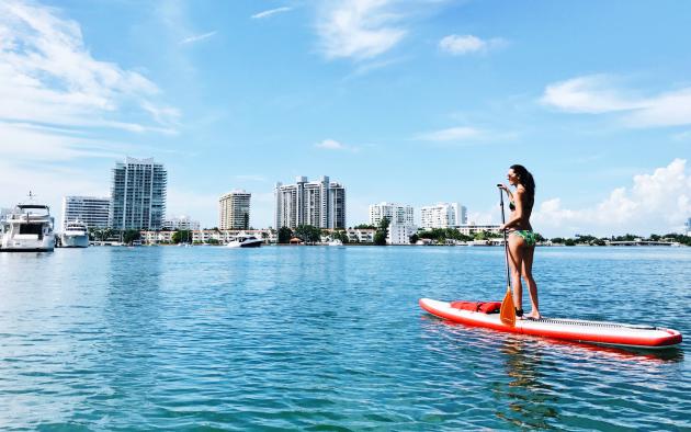 woman paddleboarding with florida skyline in background