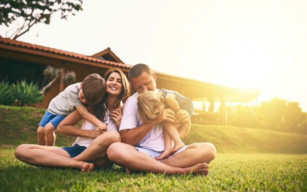 family sitting in yard outside a house