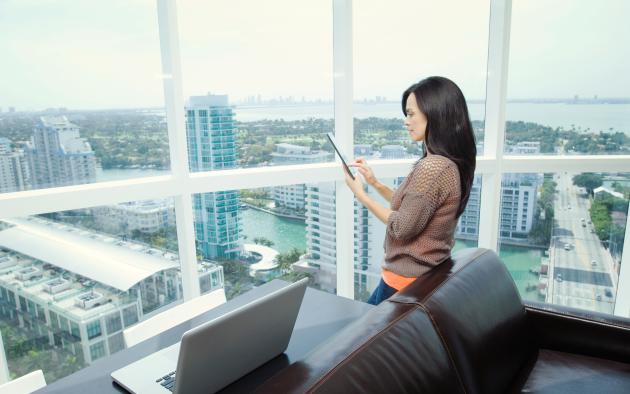 Woman with tablet in office overlooking city skyline