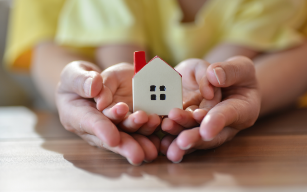 And adult and child's hands holding tiny house