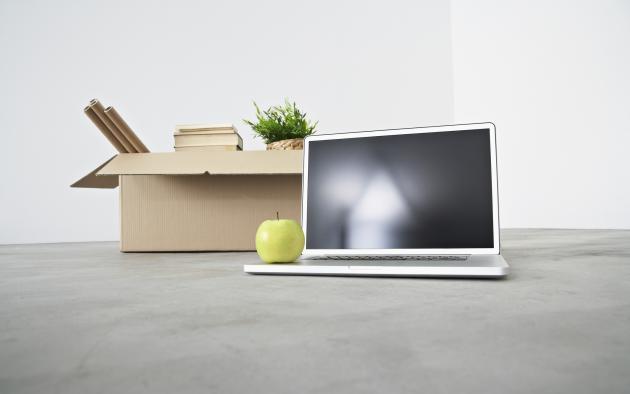 Computer with an apple on top alongside packed boxes for moving