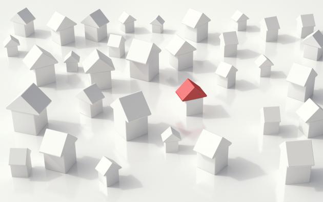 An array of toy block homes and one has a red roof