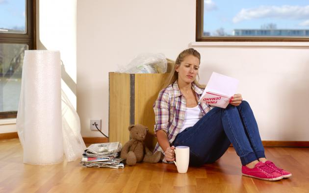 Unhappy female renter sits on the floor with a demand letter in her hand