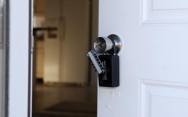 White door stands ajar with a lockbox over the outside knob