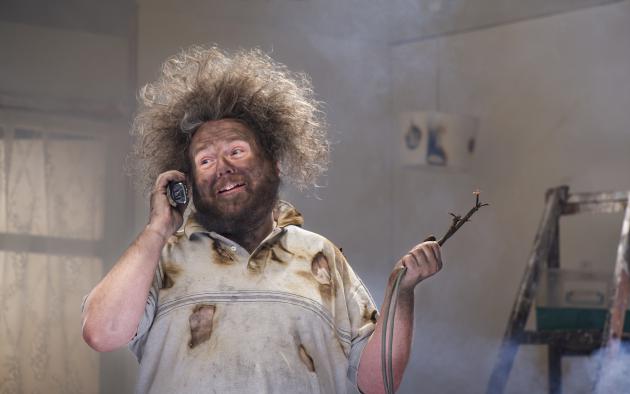 Home remodeler with blackened face and electrical wiring in one hand