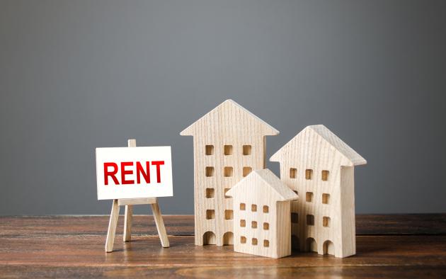 three wood block apartment buildings of different size with rent sign on easel