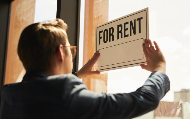 Many hangs a for-rent sign in his window