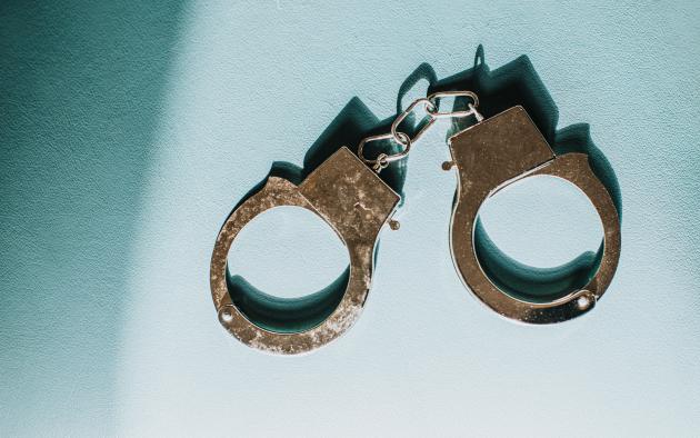 photo of metal handcuffs on a neutral blue background