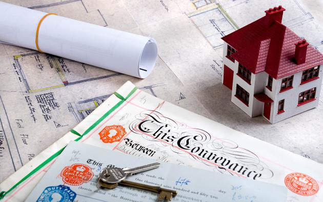 Mortgage deed with toy home, keys and blueprints
