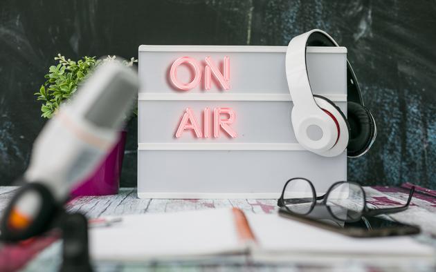 Photo of a sign that says On Air with headphones hanging on it.