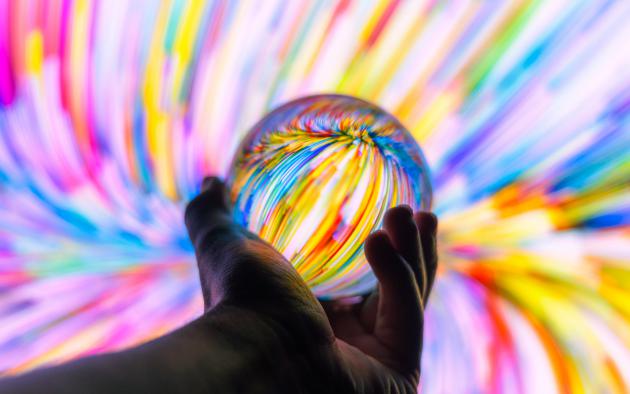 hand holding crystal ball with rainbow swirls all around it
