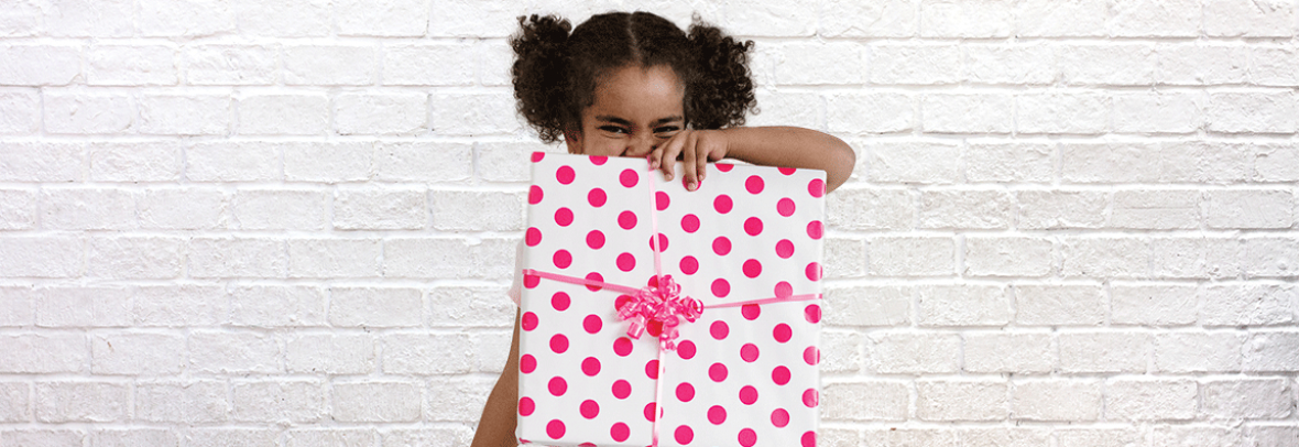 Photo of little girl holding a present wrapped in pink polka dotted wrapping paper