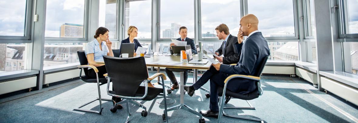 Five people sit a boardroom table with Florida landscape outside the window