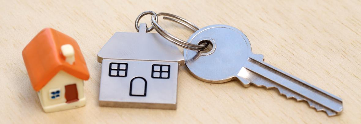 close up of small house beside metal house keychain and key