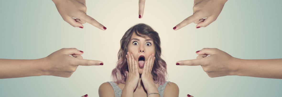 Upset woman surrounded by 7 fingers pointed at her