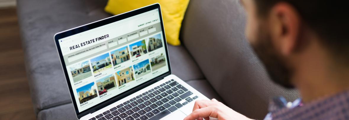 Man looking at real estate listings on a laptop