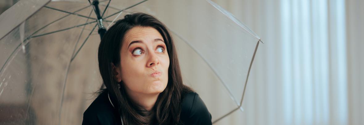 Woman sitting inside a house with a clear umbrella over her head