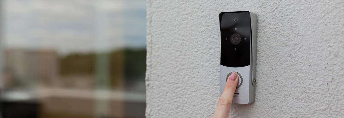Woman's finger pushes the button on a smart doorbell