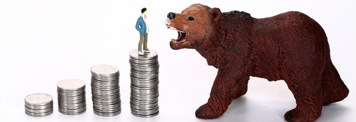 A toy bear growls at a man standing on top of a stack of coins