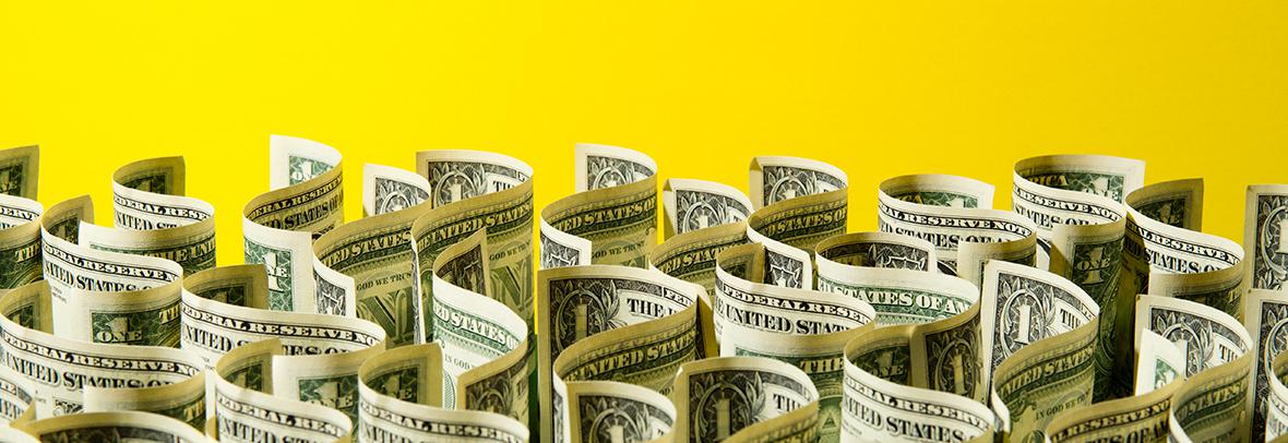 Photo illustration of dollar bills in a wavy pattern on a yellow background