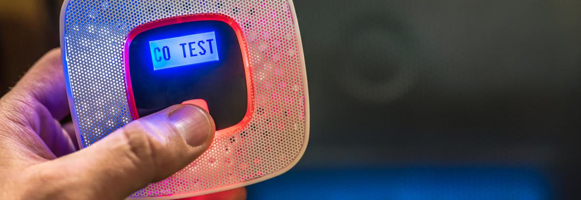 Man's thumb presses a button on a carbon monoxide tester