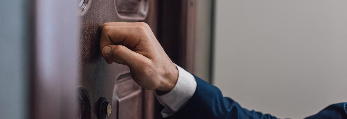 Photo of hand knocking on front door