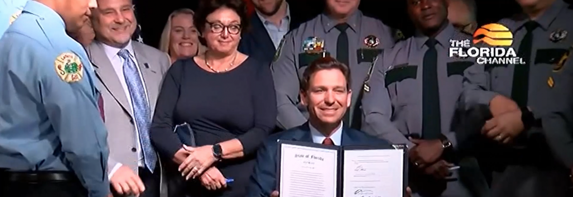 Gov. DeSantis holds up the copy of the Live Local law he signed