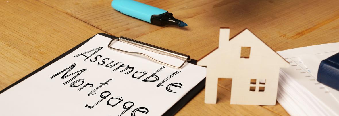 Assumable mortgage written on a clipboard and a man's hand holding the keys to a house