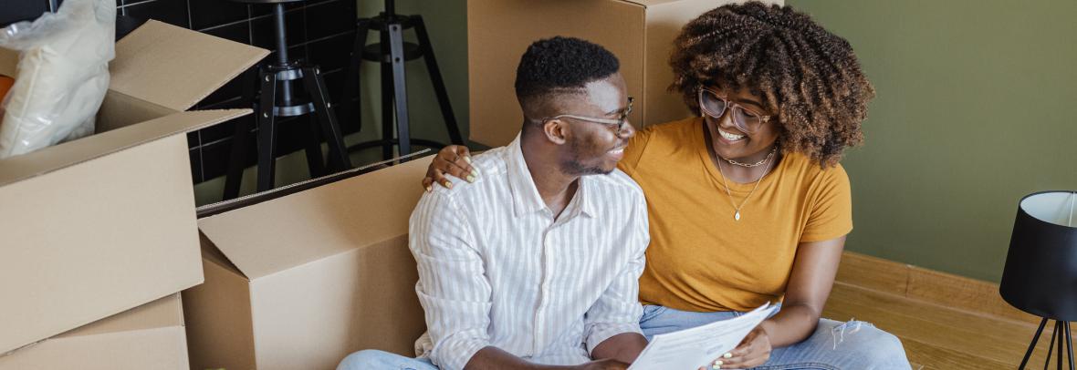 Happy renters look over their rental agreement surrounded by boxes