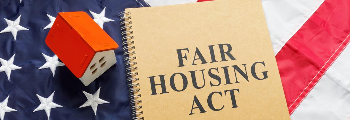 fair housing act on notebook near tiny house on American flag