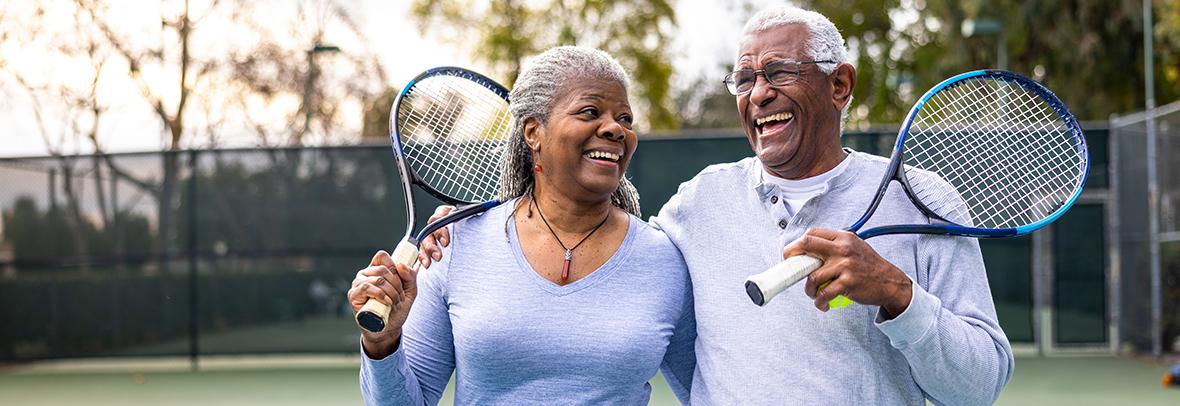 Photo of a mature African American man and woman holding tennis rackets