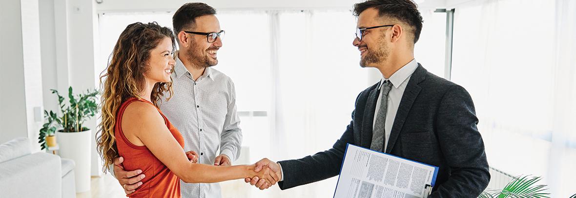 Photo of male realtor shaking the hands of a couple/clients