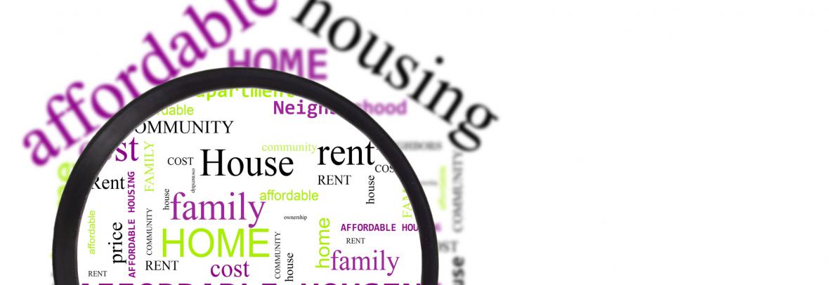 hand with magnifying glass over affordable housing word cloud
