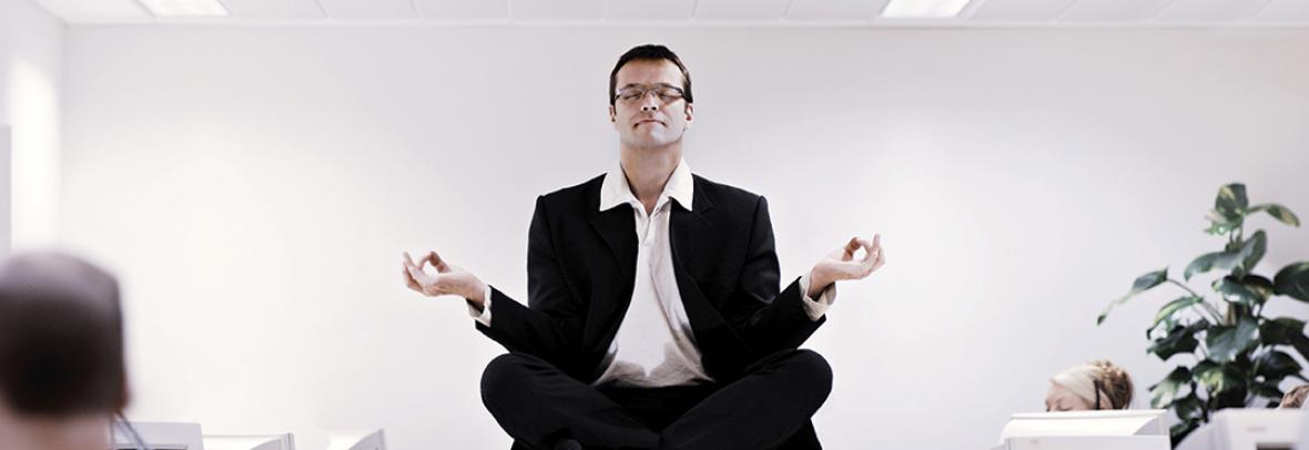 Photo of a business man sitting on a desk meditating